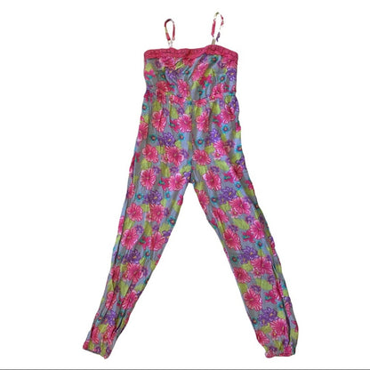 A girls jumpsuit with a vibrant floral print in pink, purple, and green on a light blue-gray base, shown flat against a white background.