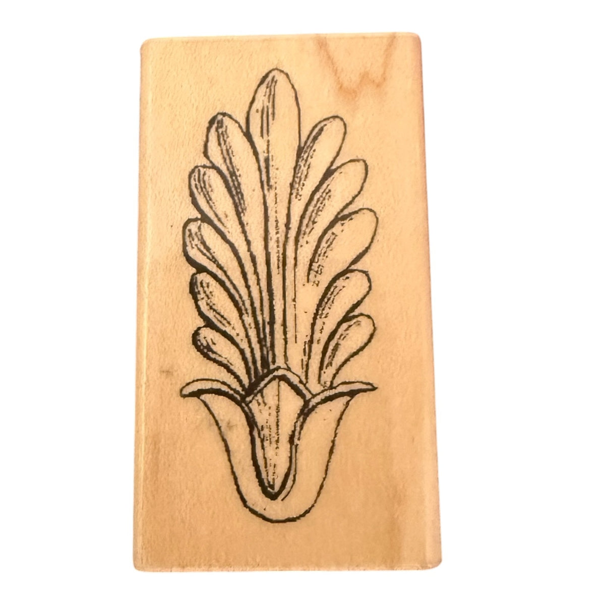 A rectangular wooden rubber stamp featuring a black ink botanical design of a stylized leaf , shown on a plain white background.
