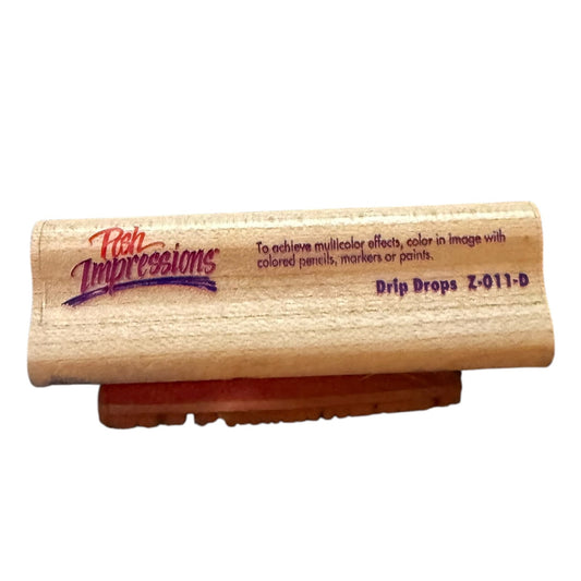 A wooden rubber stamp with the brand name 'Fish Impressions' and model 'Drip Drops Z-011-D' printed on the side, resting on a small brown stand against a white background.