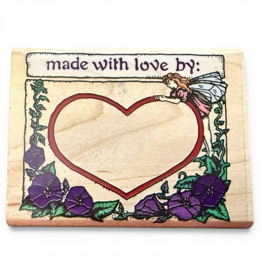 Wooden stamp with heart design, fairy, and flowers on a white background
