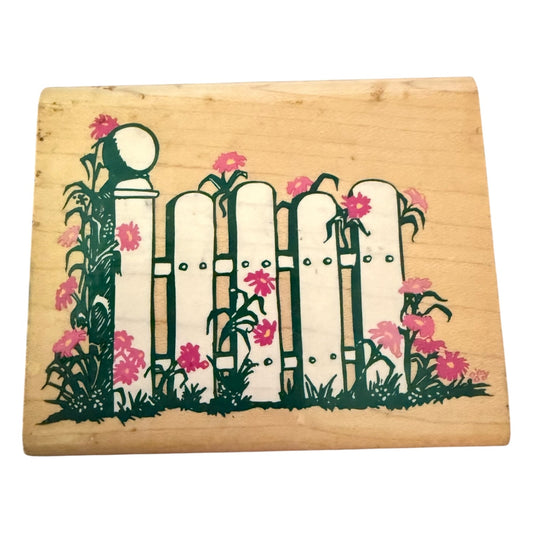 Wooden stamp block with a decorative design of a fence and flowers on a white background