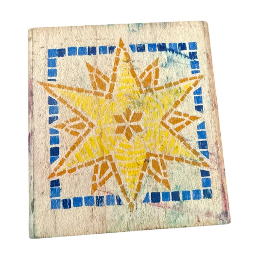 Decorative rubber stamp with  tile with a yellow star design on a blue grid background