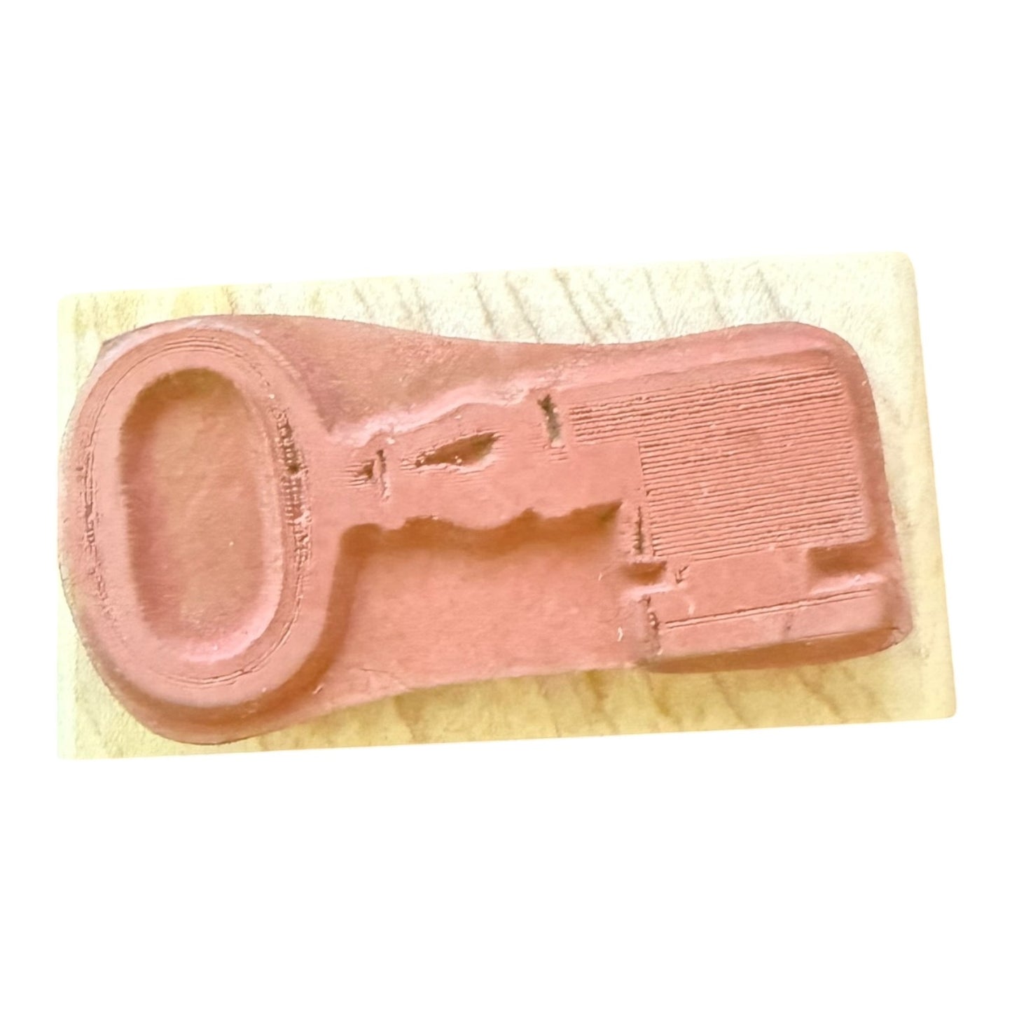 Pink rubber stamp on a wooden block with a plain background