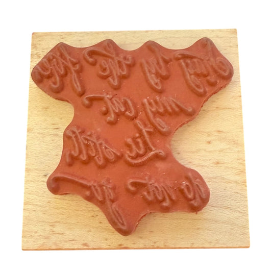 Red rubber stamp with wavy text design on a wooden block