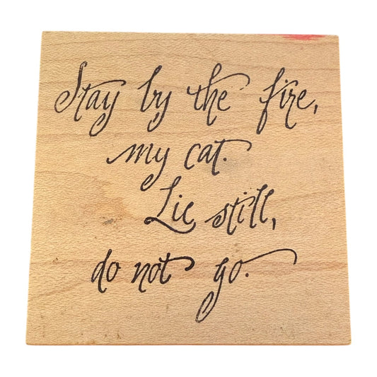 Wooden block with engraved text 'Stay by the fire, my cat. Lie still, do not go.'