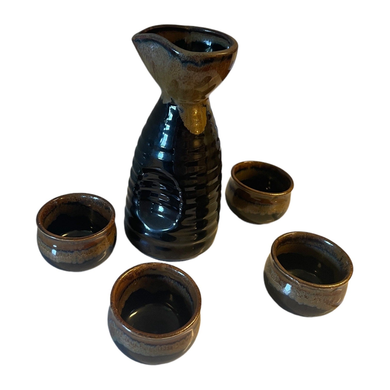 A five-piece ceramic sake set featuring a glossy dark blue-black carafe and four matching small cups with brown and gold glaze accents, arranged on a plain white background.