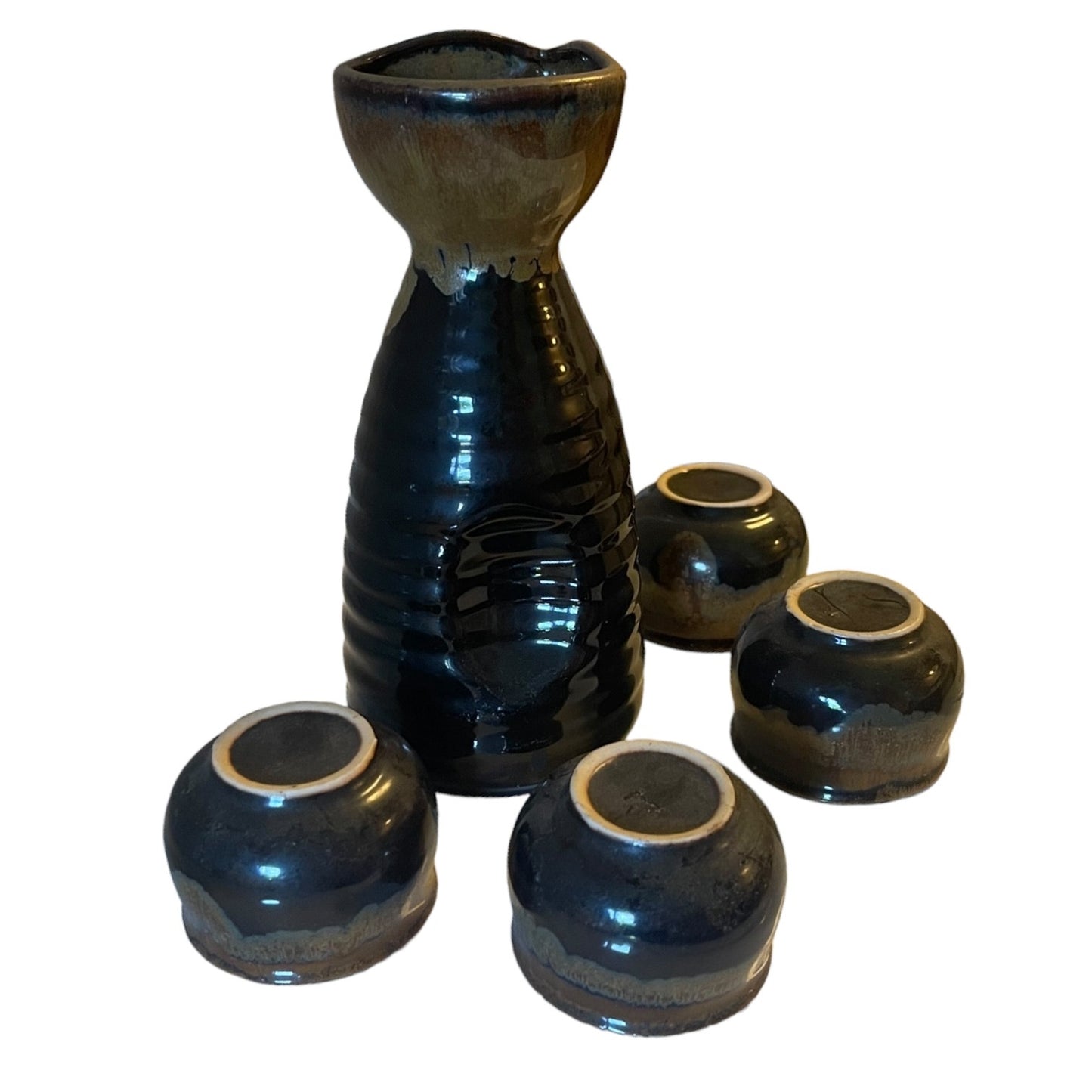 A ceramic sake set featuring a tall, ribbed sake holder in a glossy black glaze with a natural brown edge, accompanied by four matching small tumblers, all photographed on a plain white background.