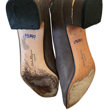 A pair of dark brown heels shown from the soles, revealing a tan insole with hand-written numbers and visible scuffing and wear on the leather.