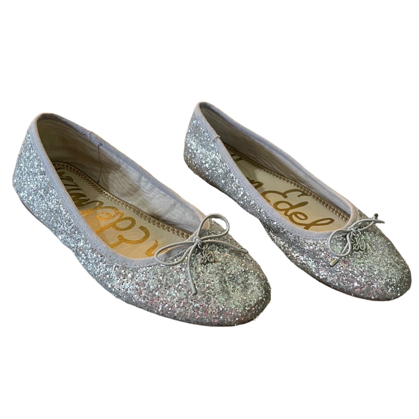 A pair of silver glitter ballet flats with small bow details on the toes, shown against a plain white background. 