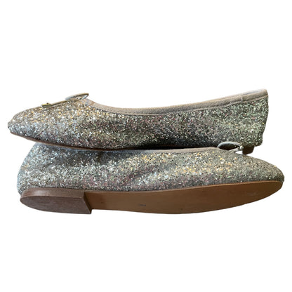A pair of glittery silver ballet flats with a small bow detail on the toe, shown against a plain white background.