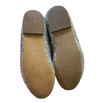 A pair of flats shown from the bottom, featuring silver glitter uppers with a tan sole and a brown heel cap, on a white background.