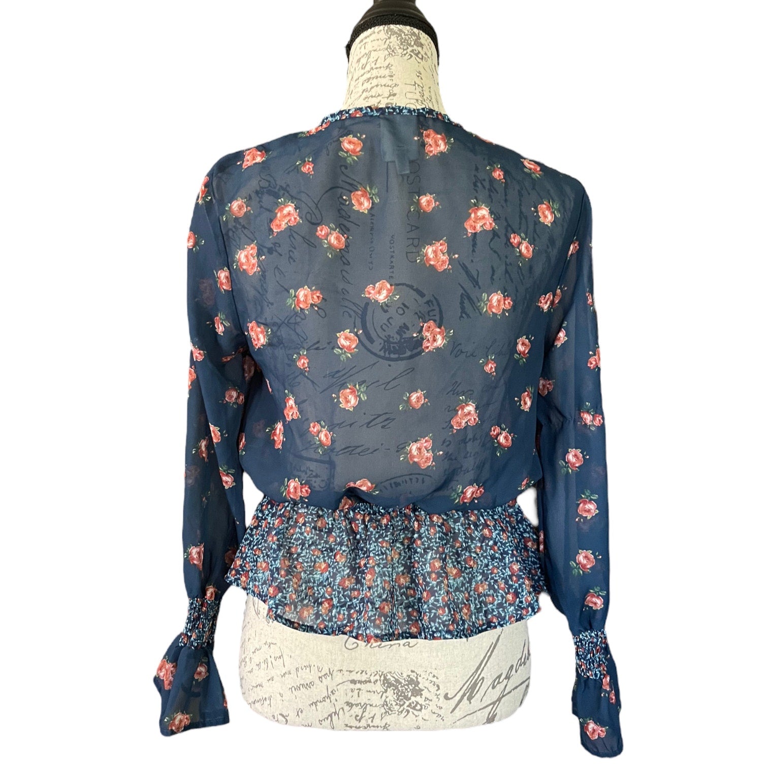 Back of blue blouse with floral pattern on a mannequin against a white background