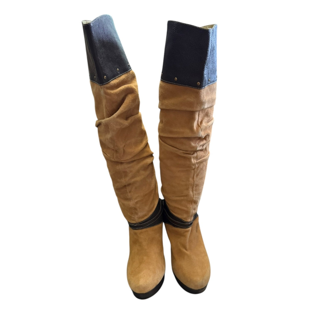 A pair of slouchy knee-high boots in tan suede with brown trim, shown against a plain white background.
