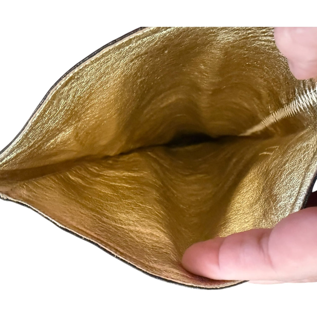 Close-up of a metallic gold interior being held open by fingers against a white background.