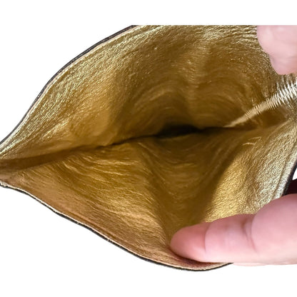 Close-up of a metallic gold interior being held open by fingers against a white background.