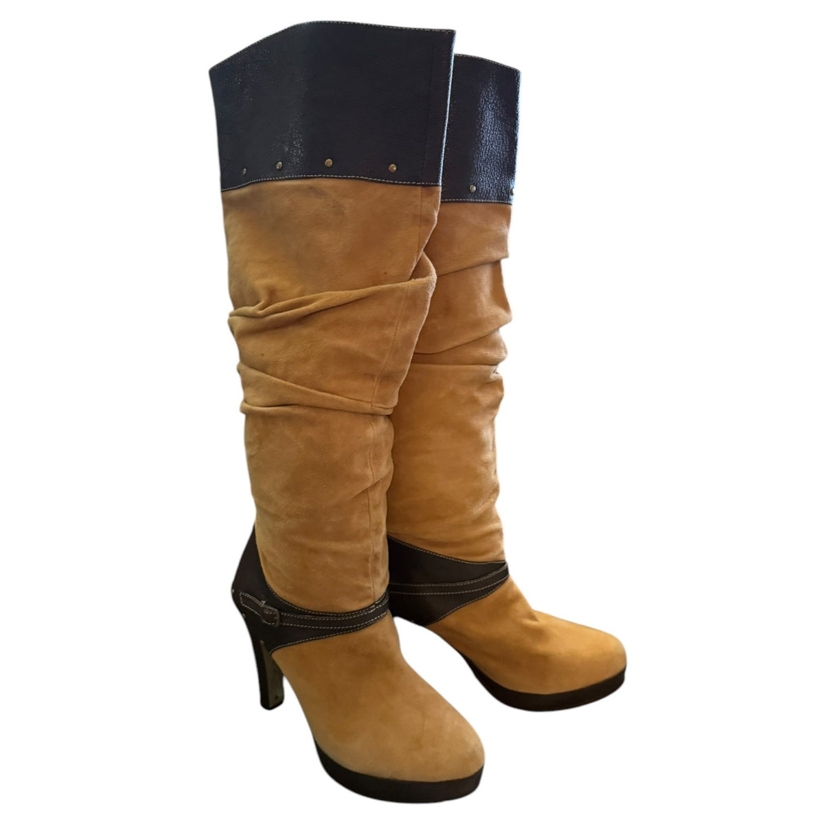 A pair of slouchy knee-high boots in tan suede with brown trim and a high stiletto heel, shown against a plain white background.