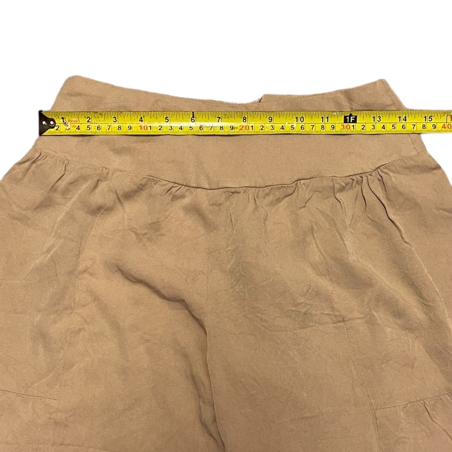 Waist measurements of pants with yellow tape measure stretched across the waistband to show the measurement.