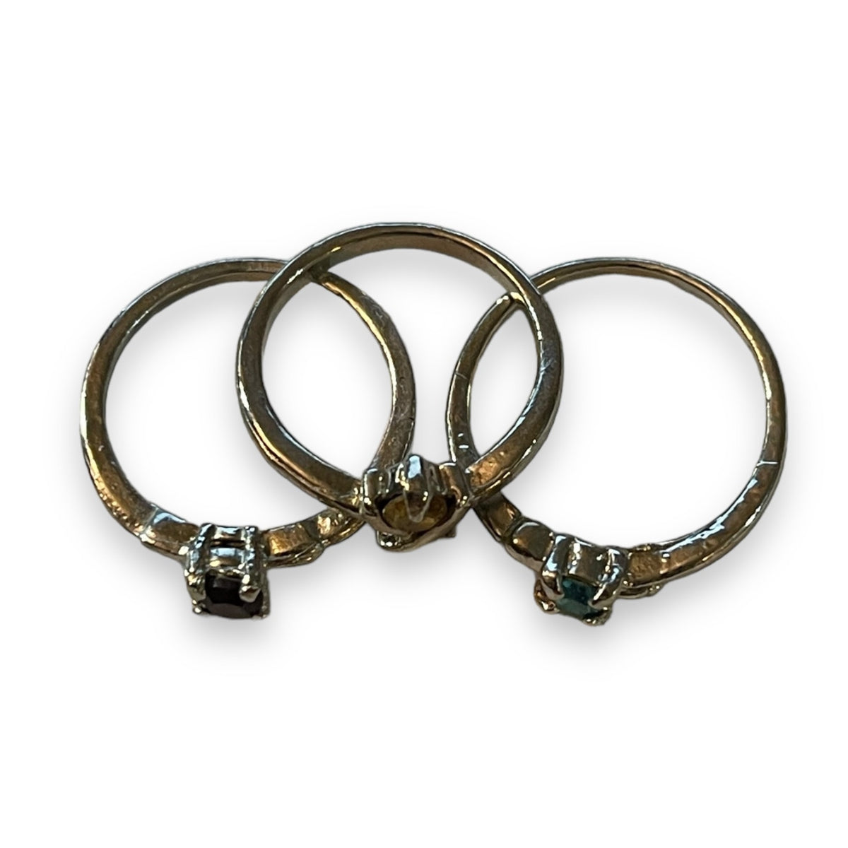 Three silver rings with small round-cut gemstones, arranged overlapping on a plain white background.