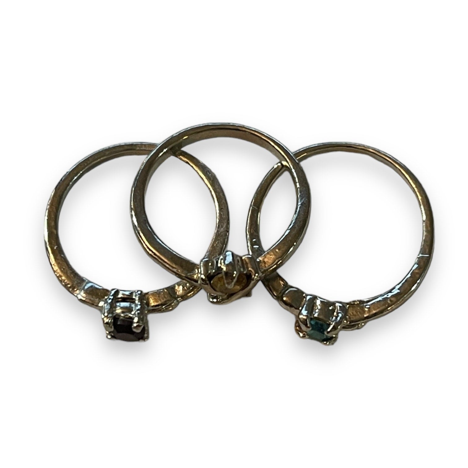 Three silver rings with small round-cut gemstones, arranged overlapping on a plain white background.