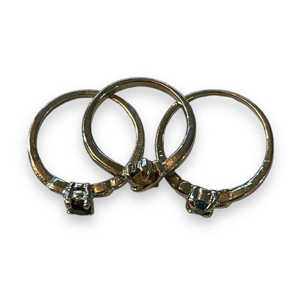 Three silver rings with small round-cut gemstones, arranged overlapping on a plain white background.