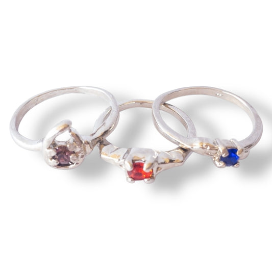 Three silver rings with colored gemstones on a white background