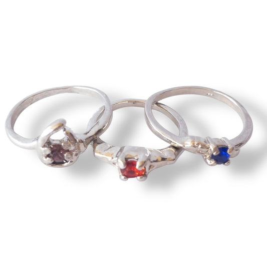 Three silver rings with colored gemstones on a white background