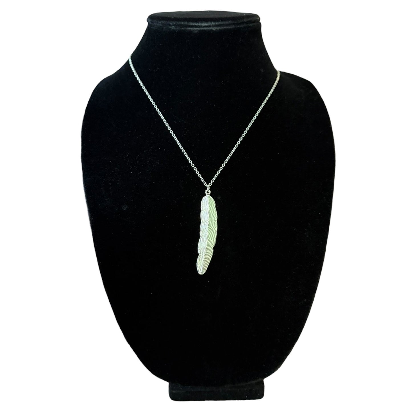 A silver chain necklace with a silver feather pendant, displayed on a black velvet neck mannequin against a white background.