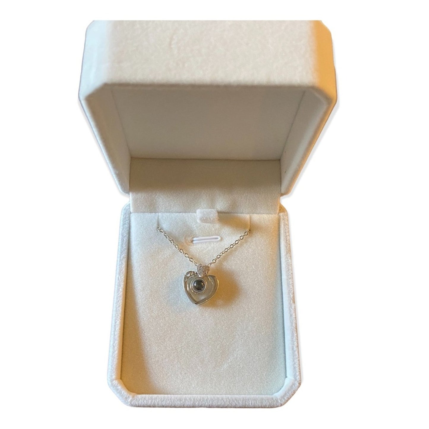 Silver necklace with a heart pendant in an open jewelry box on a white background