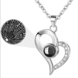 Silver necklace with a heart and circular pendant on a white background