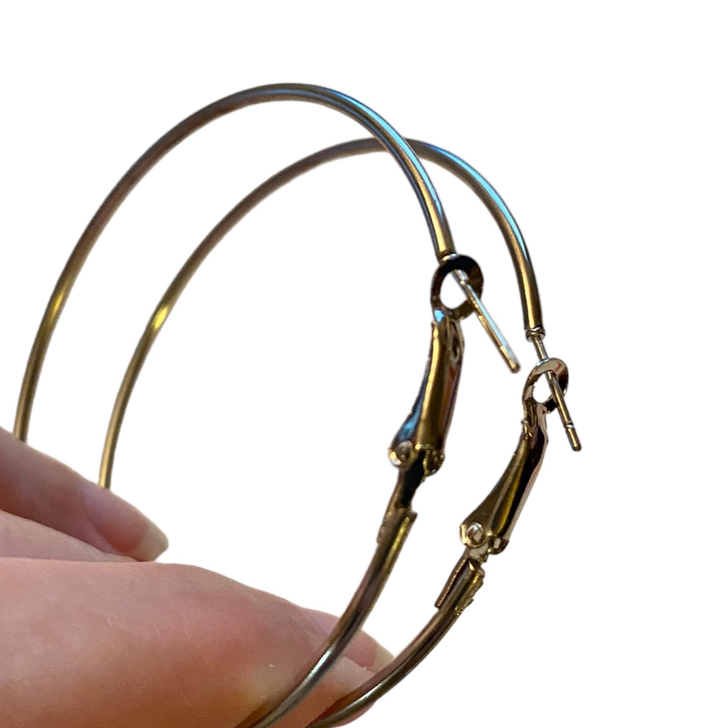 silver-toned metal hoop earrings with spring-ring closures, shown being held by a hand against a plain white background.