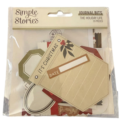A package of Simple Stories Journal Bits 'The Holiday Life' set, containing 33 pieces of scrapbooking paper and embellishments in a clear plastic bag with a beige header card.