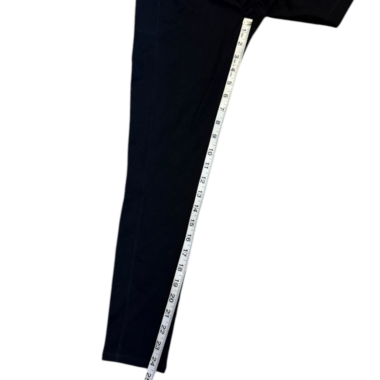Black pants inseam with a measuring tape draped over it on a white background