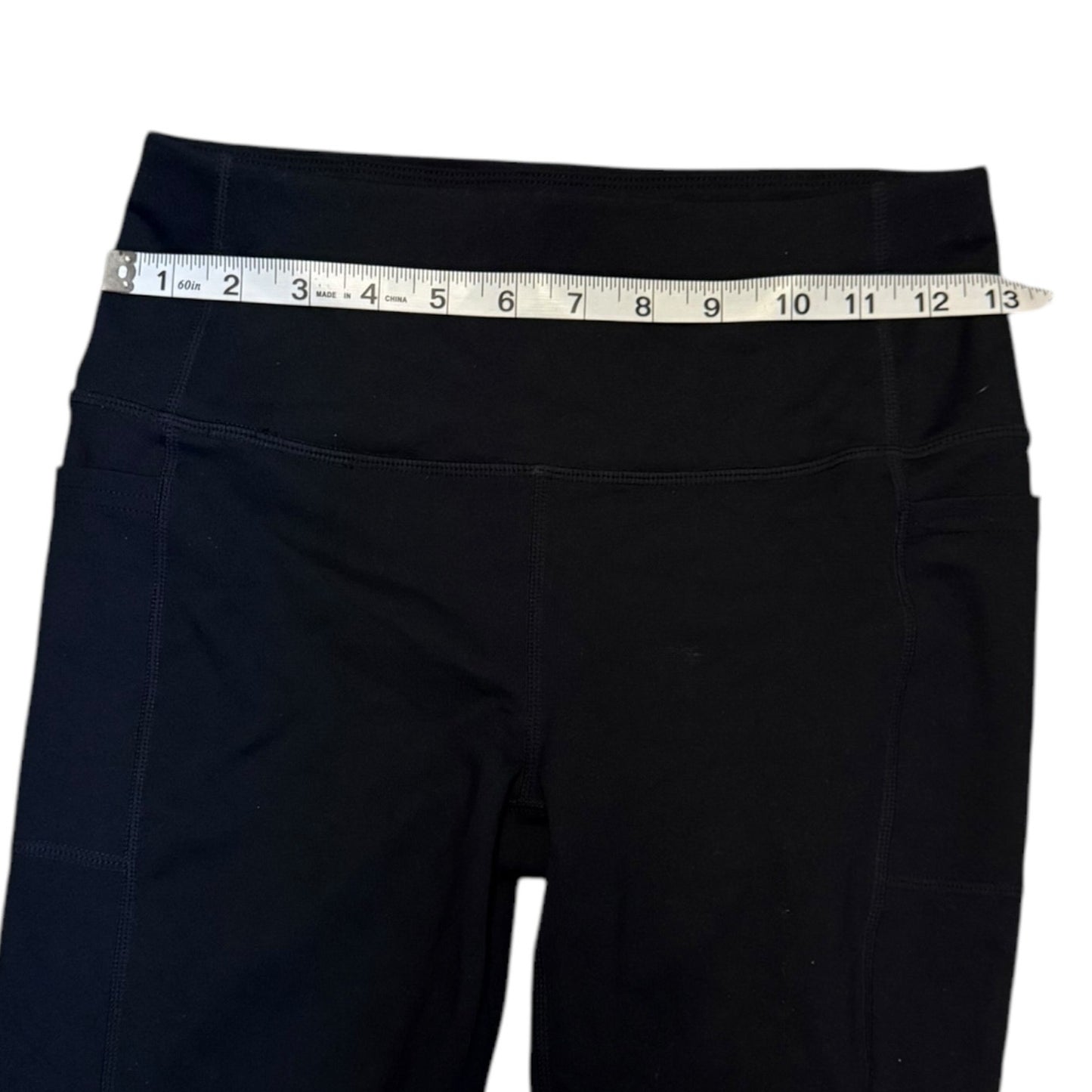 Black pants with a measuring tape around the waist on a white background