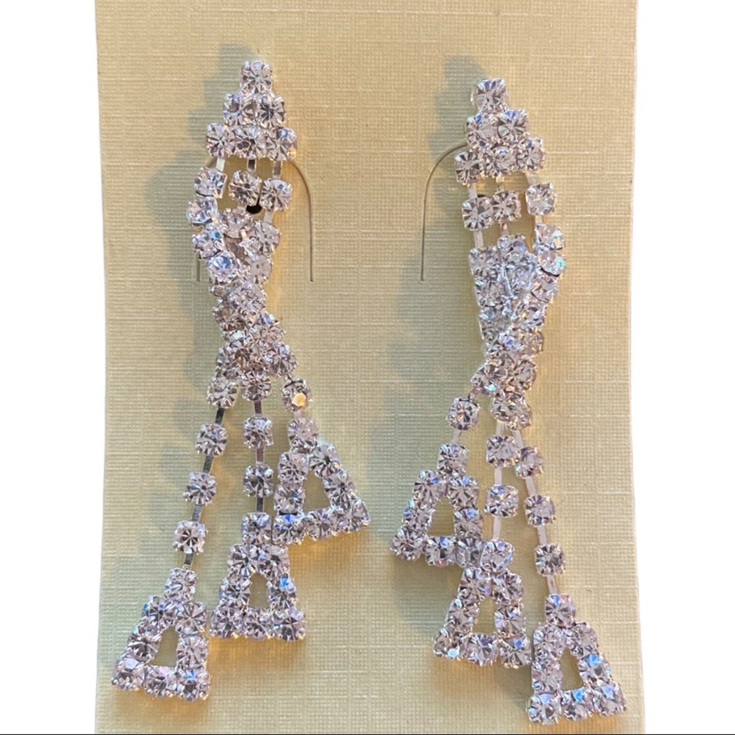 Pair of silver earrings with clear stones on a beige background