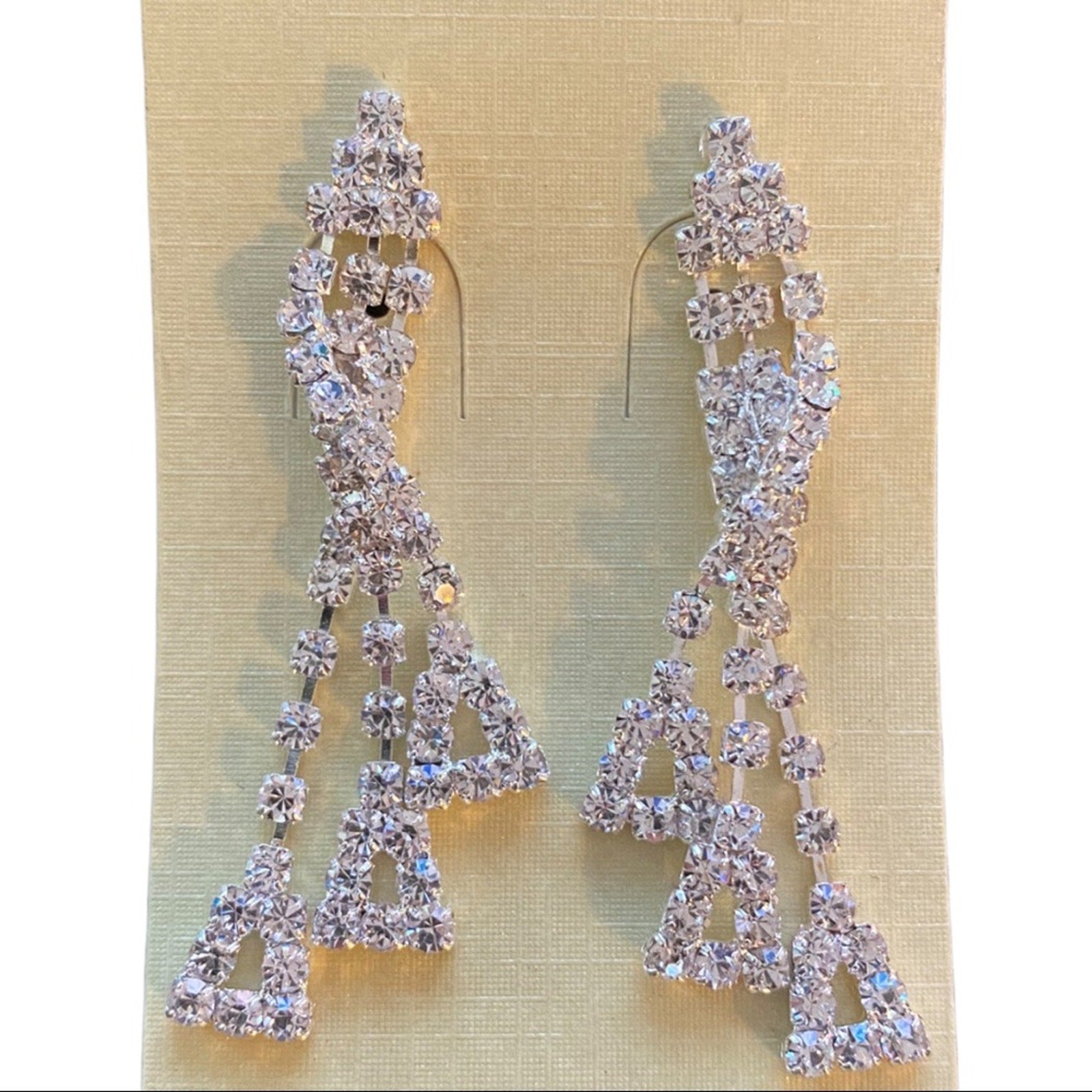Pair of silver earrings with clear stones on a beige background