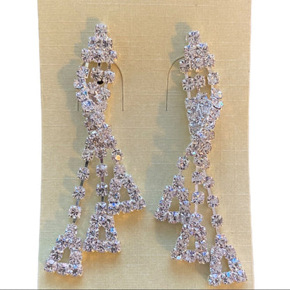 Pair of silver earrings with clear stones on a beige background