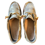 Top of a Pair of Sperry shoes with gold accents on a white background