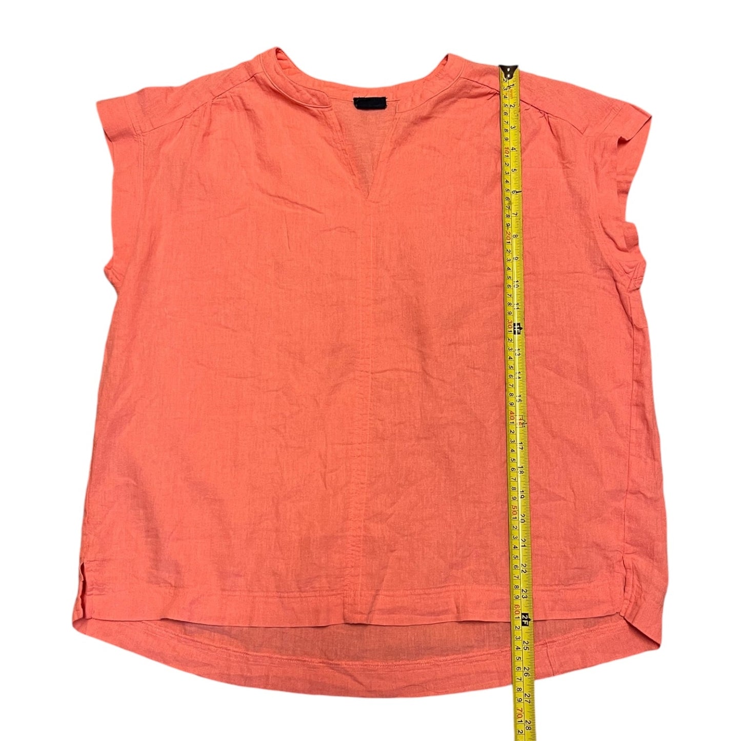 Coral sleeveless top with a measuring tape on a white background