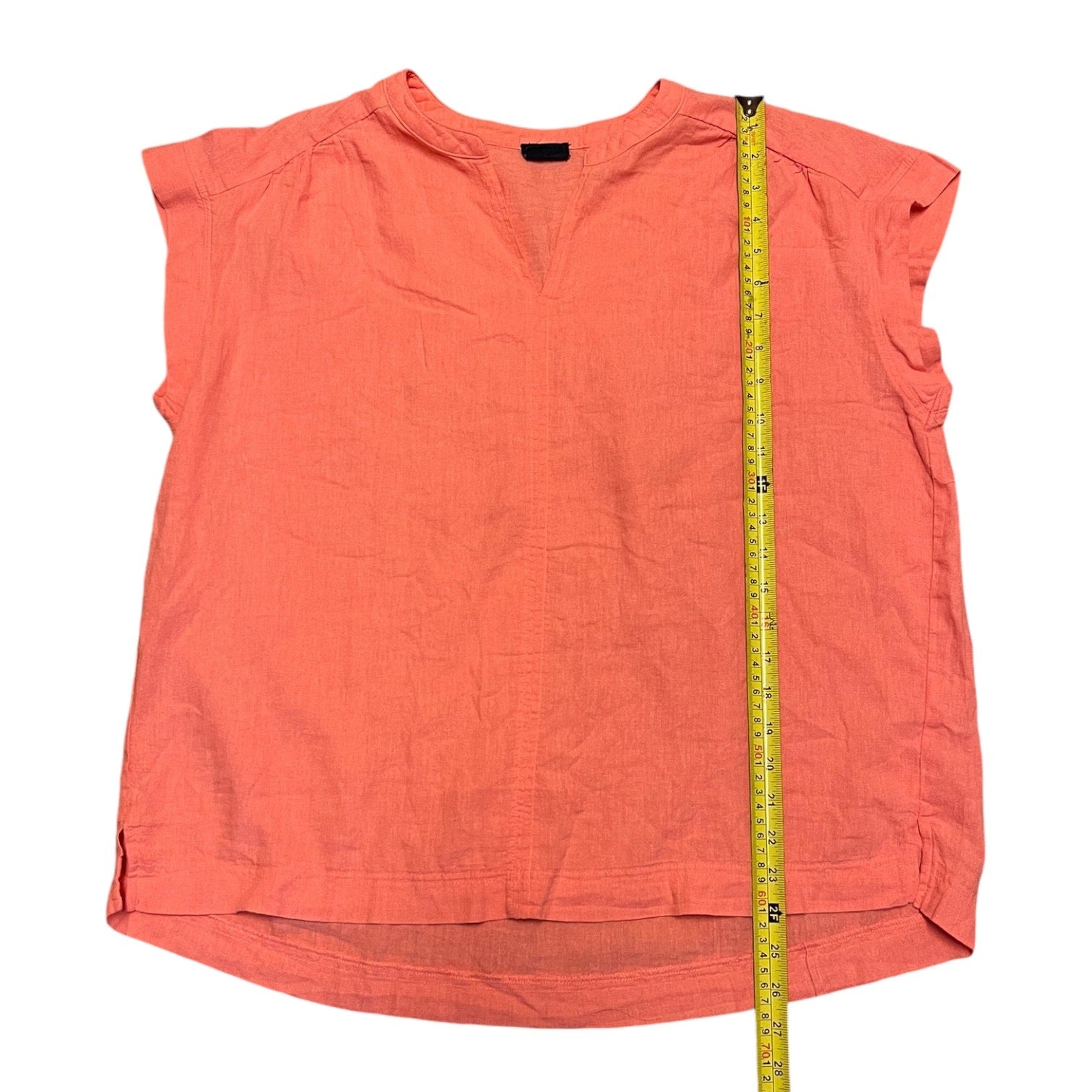 Coral sleeveless top with a measuring tape on a white background
