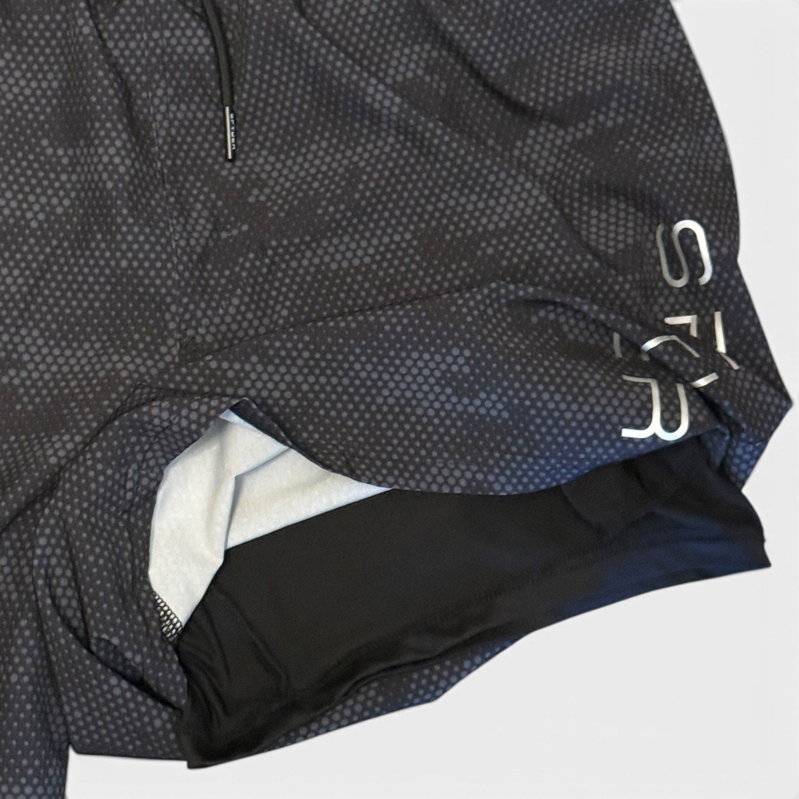 Close-up of a black and gray textured shorts with a brand logo on a white background