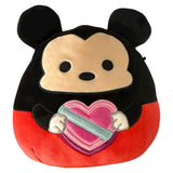Plush toy resembling a character with black ears and red body holding a heart-shaped object on a white background