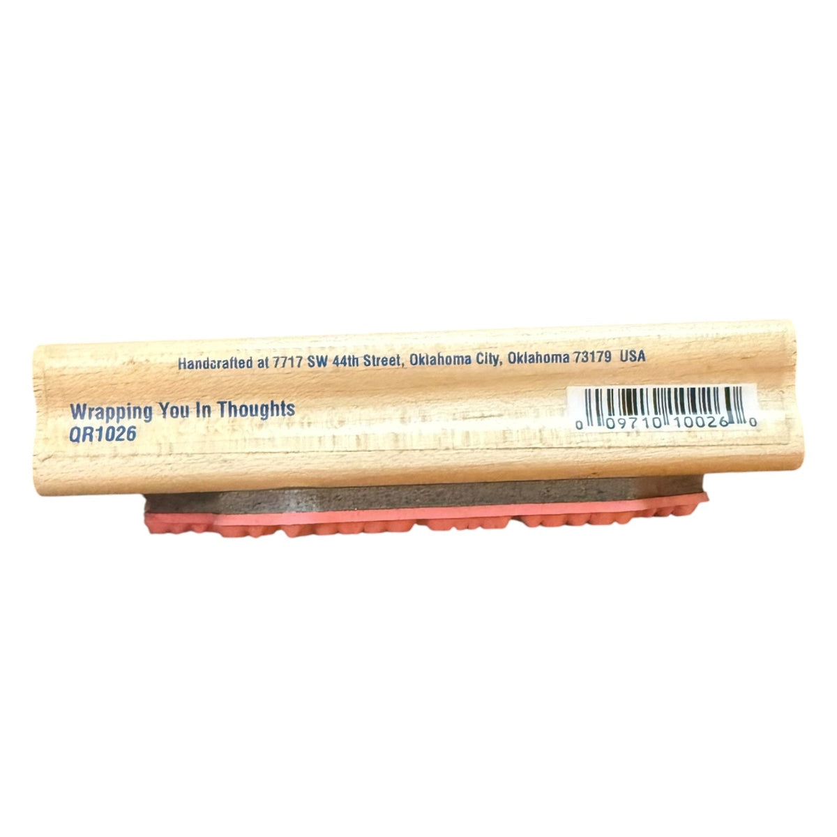 A wooden rubber stamp with the text 'Wrapping You In Thoughts QR1026' printed on the stamp block, featuring a natural wood black, a gray base, and a red rubber stamp face, shown against a plain white background.