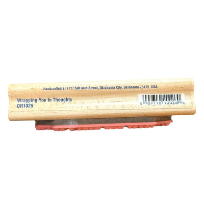 A wooden rubber stamp with the text 'Wrapping You In Thoughts QR1026' printed on the stamp block, featuring a natural wood black, a gray base, and a red rubber stamp face, shown against a plain white background.