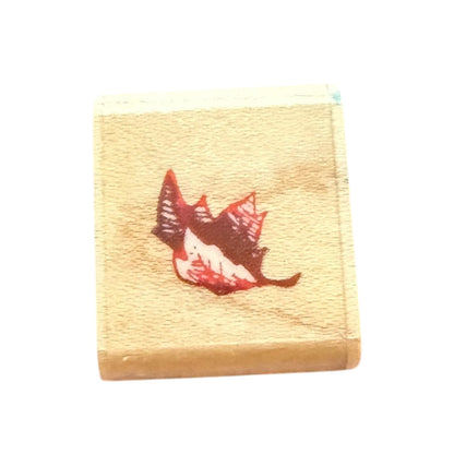 Wooden stamp with a red and brown leaf design on a white background