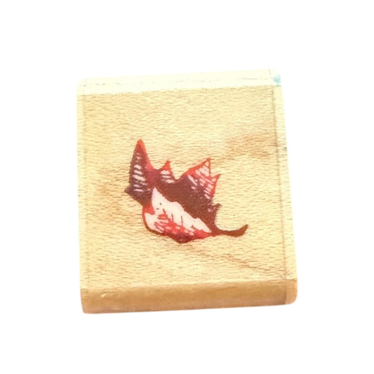 Wooden stamp with a red and brown leaf design on a white background