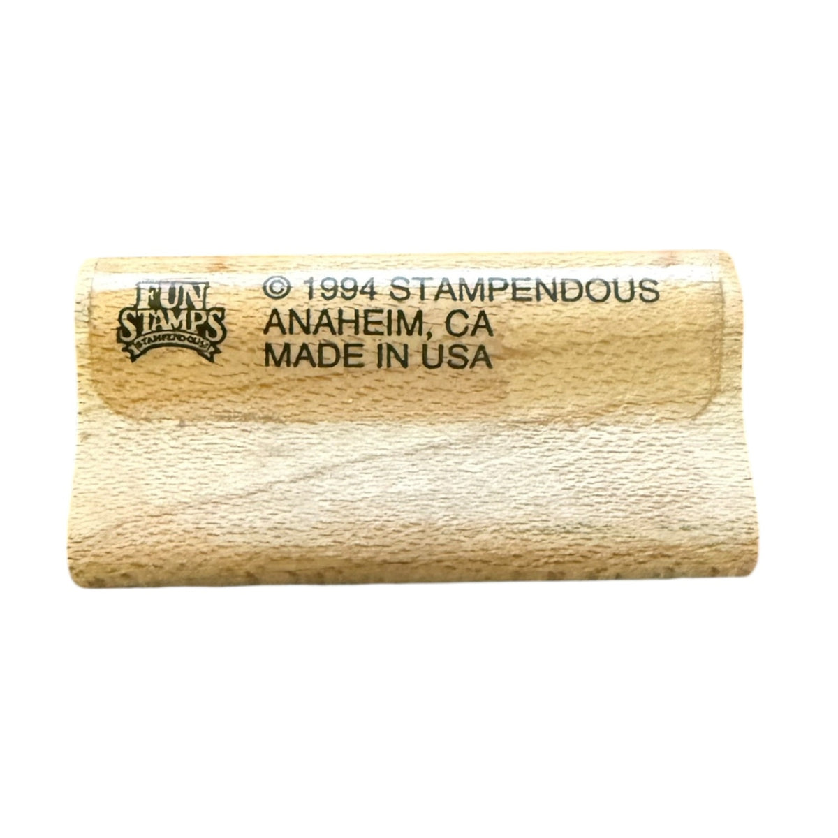 A close-up of a wooden stamp blank with black printed text reading 'FUN STAMPS' and '© 1994 STAMPENDOUS ANAHEIM, CA MADE IN USA' on a plain white background.