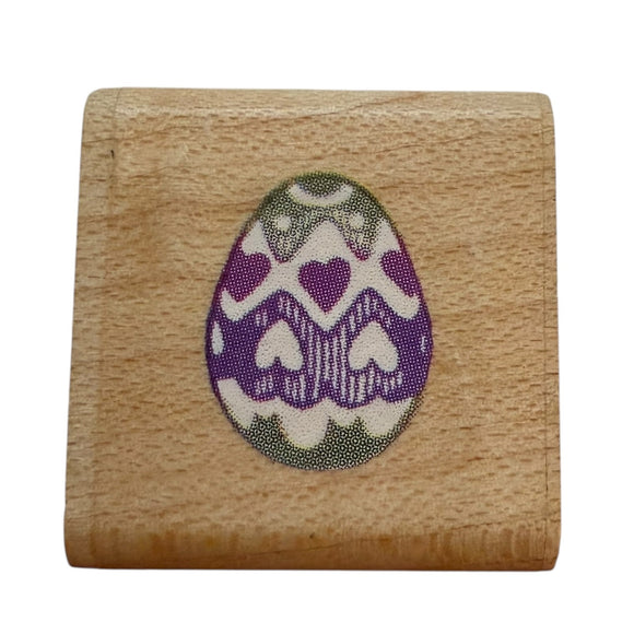 Wooden stamp with a purple and white egg design on a wooden block