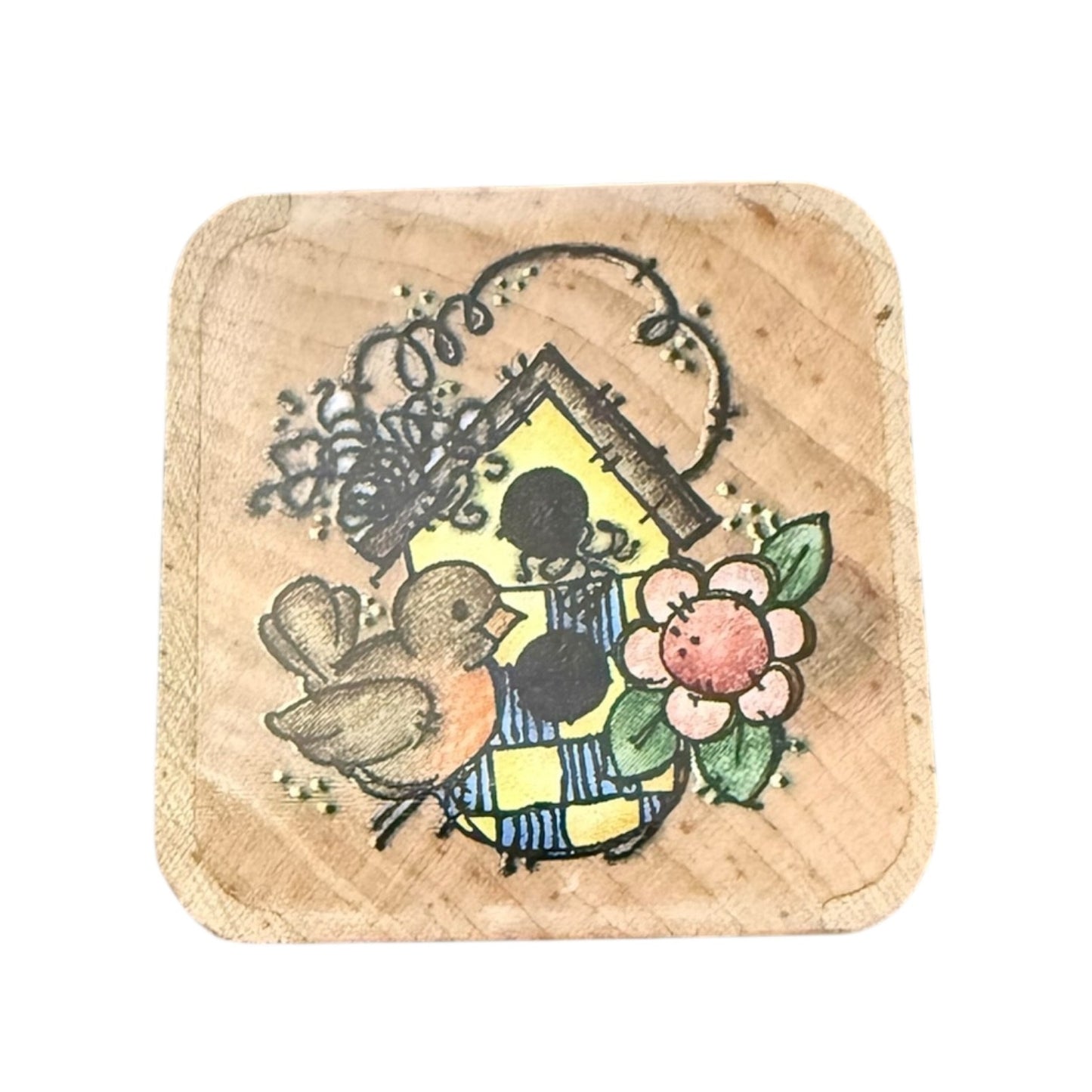 Wooden stamp with a bird, birdhouse and flowers on a white background.