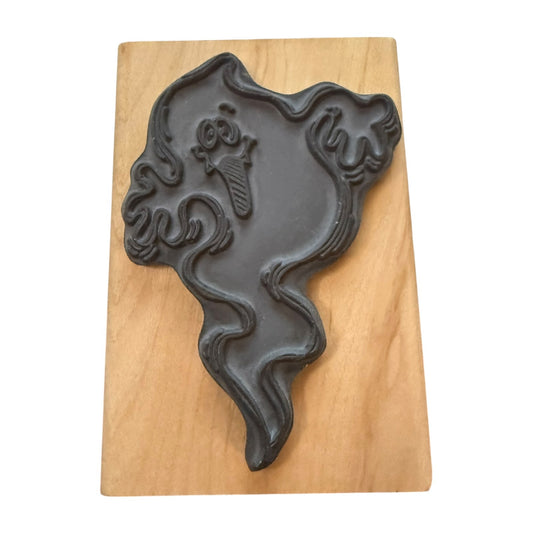A dark gray rubber stamp ghost displayed on a rectangular light brown wooden block against a white background.
