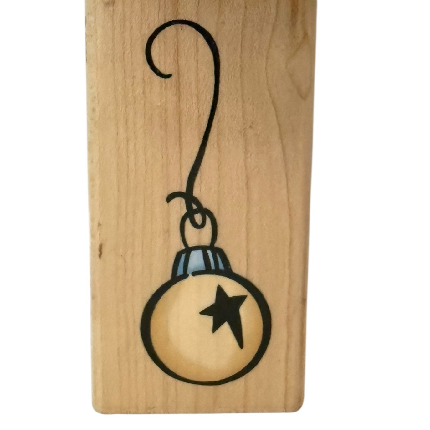 Wooden block with a black line drawing of a Christmas ornament on a white background